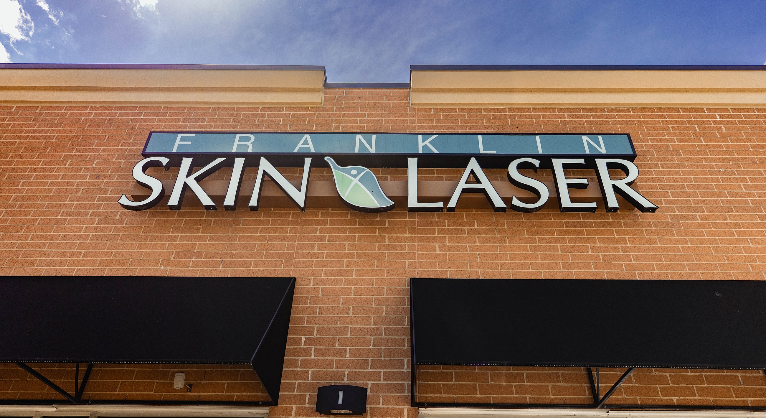 Franklin Skin Laser storefront sign against blue sky.